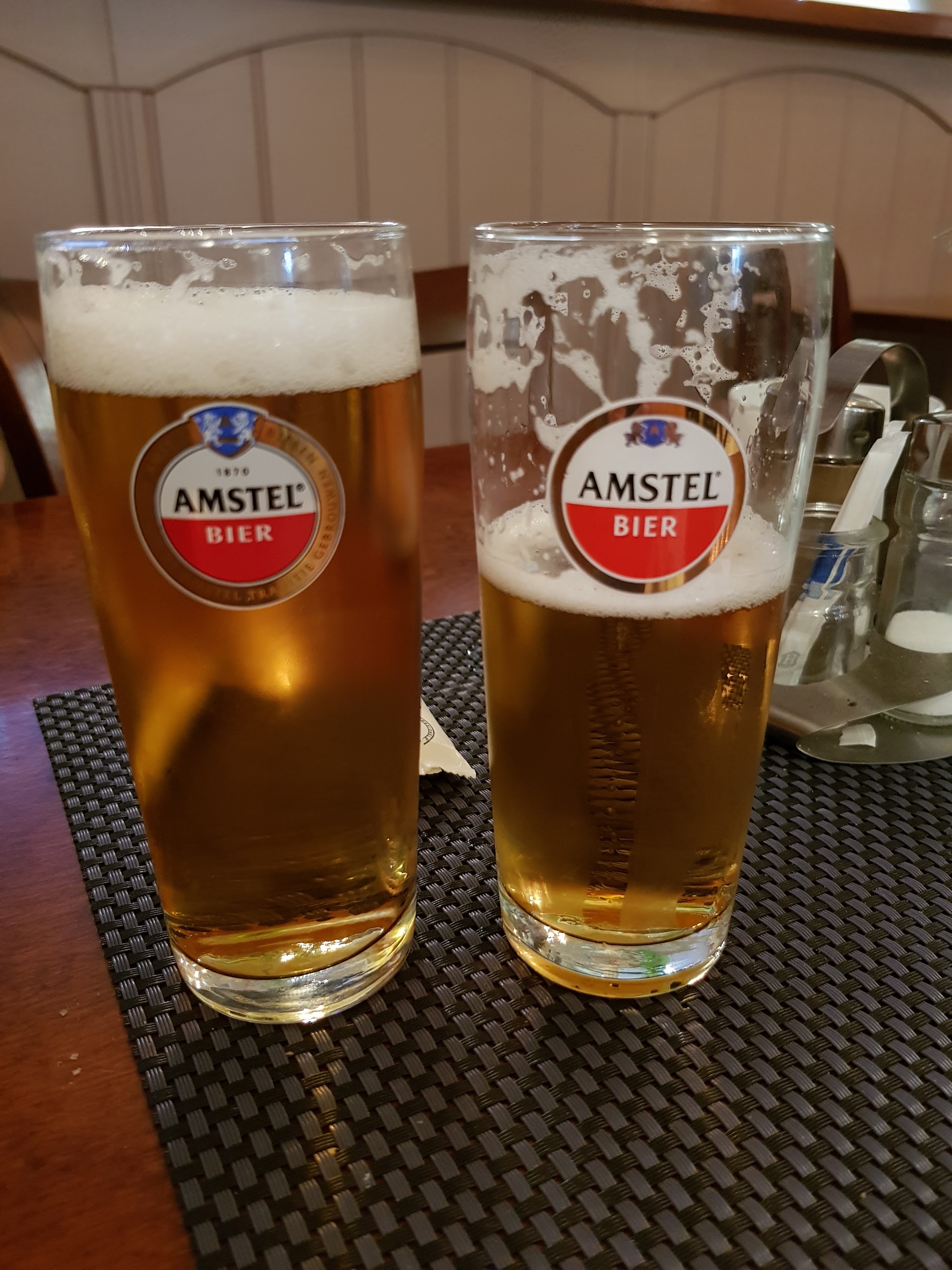 Twee glazen bier op een placemat aan tafel
