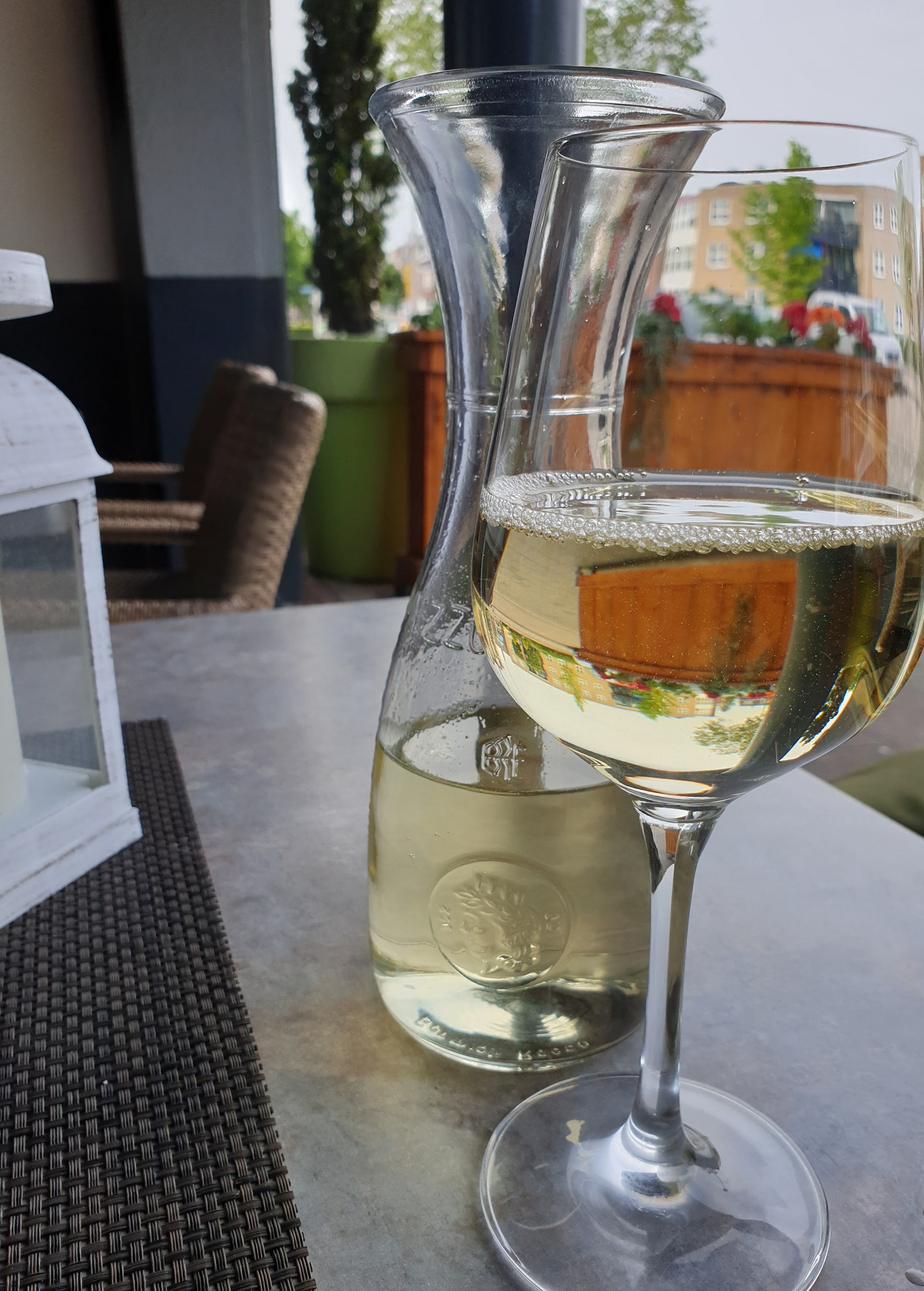 Karaf en glas witte wijn op een terrastafel voor de deur
