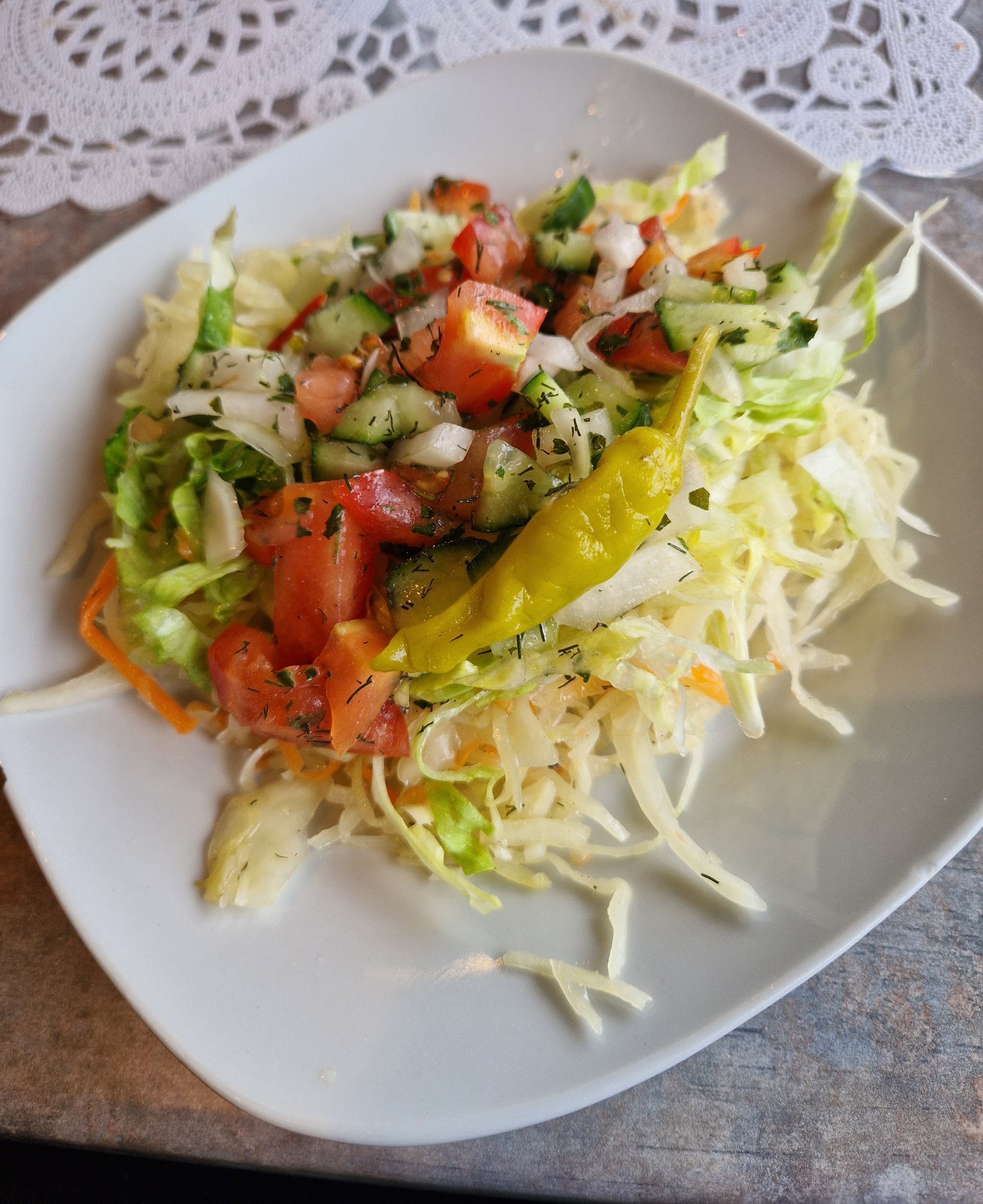 Huissalade met witte kool, tomaat, komkommer, ui, dille en pepperoncini